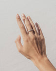 Hand wearing a ring and bracelet on a plain background