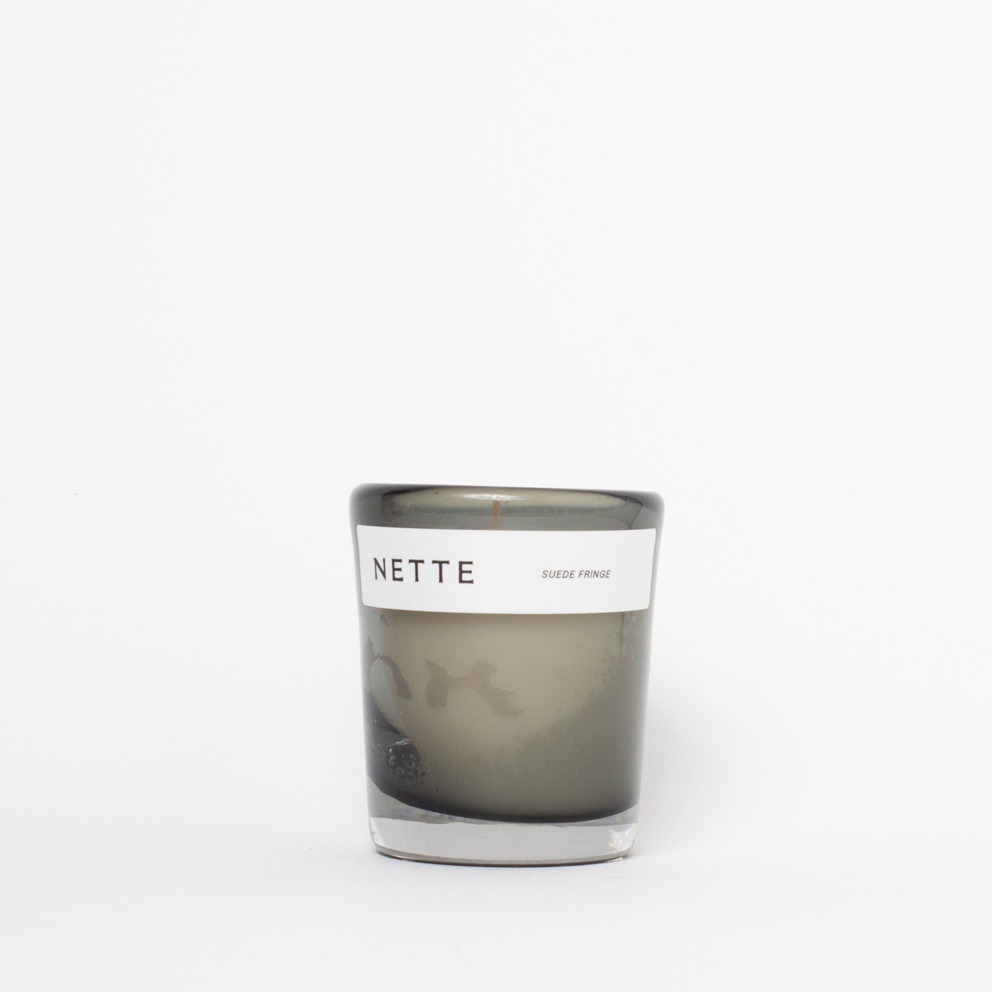 Candle in a glass jar with a white label on a white background